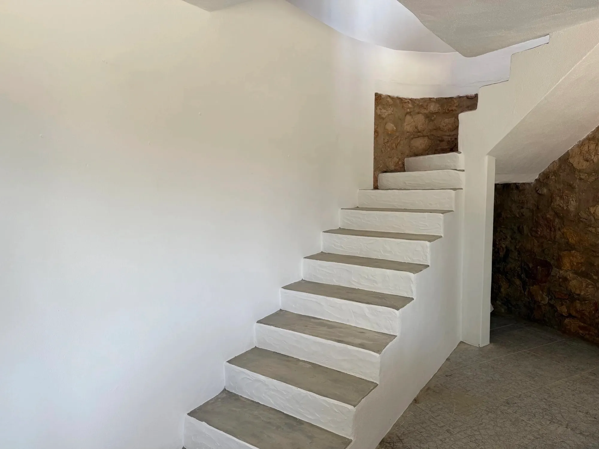 Tiled interior staircase next to an exposed stone wall